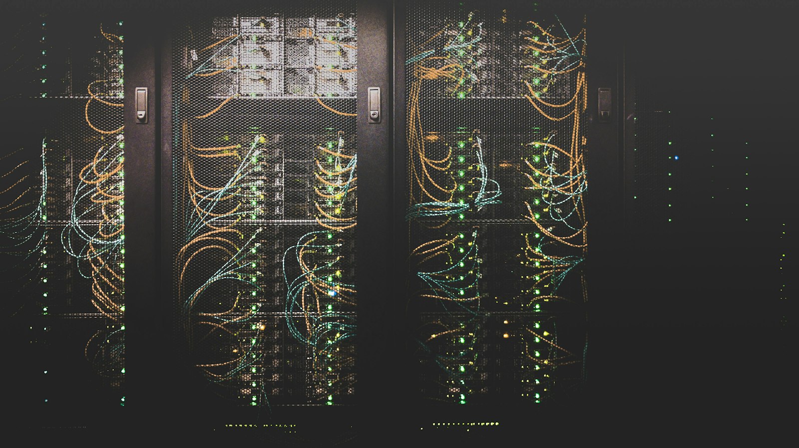 Server cabinets with network cabling and status lights behind mesh doors.